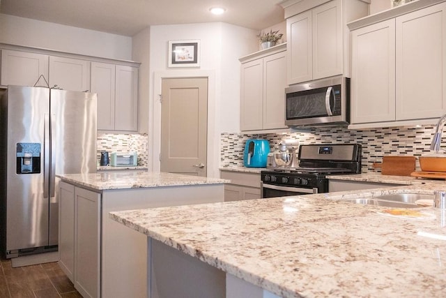 kitchen with light stone countertops, appliances with stainless steel finishes, tasteful backsplash, and sink