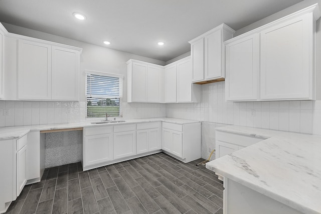 kitchen featuring light stone countertops, white cabinetry, dark wood-type flooring, and sink