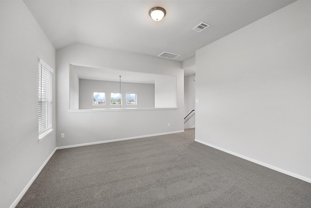 unfurnished room with lofted ceiling and dark colored carpet