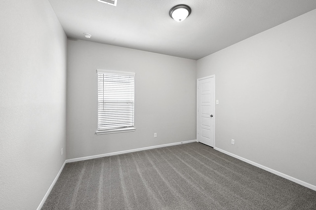 spare room featuring dark colored carpet