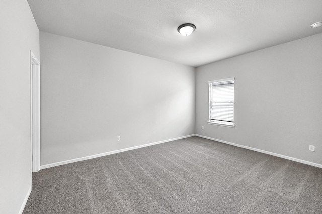 empty room featuring a textured ceiling and dark carpet