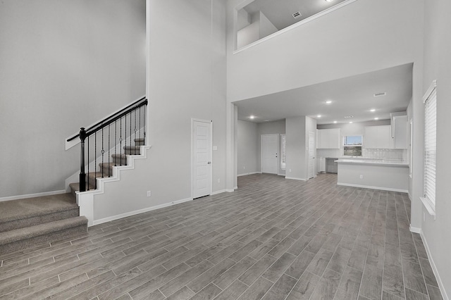 unfurnished living room featuring a high ceiling and light wood-type flooring