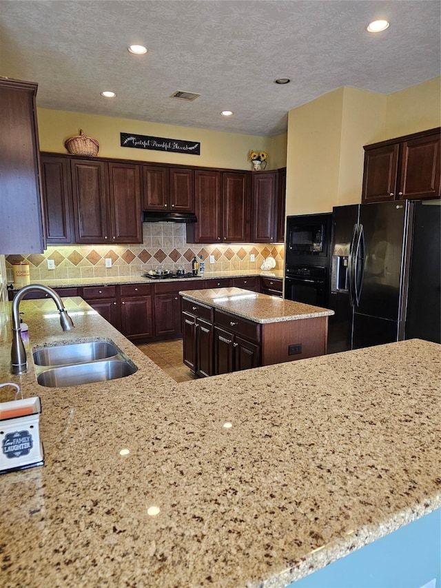 kitchen featuring light stone counters, sink, and black appliances