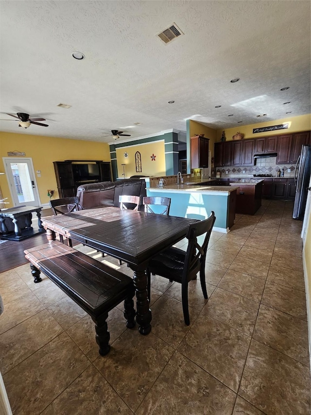 tiled dining room with ceiling fan and a textured ceiling