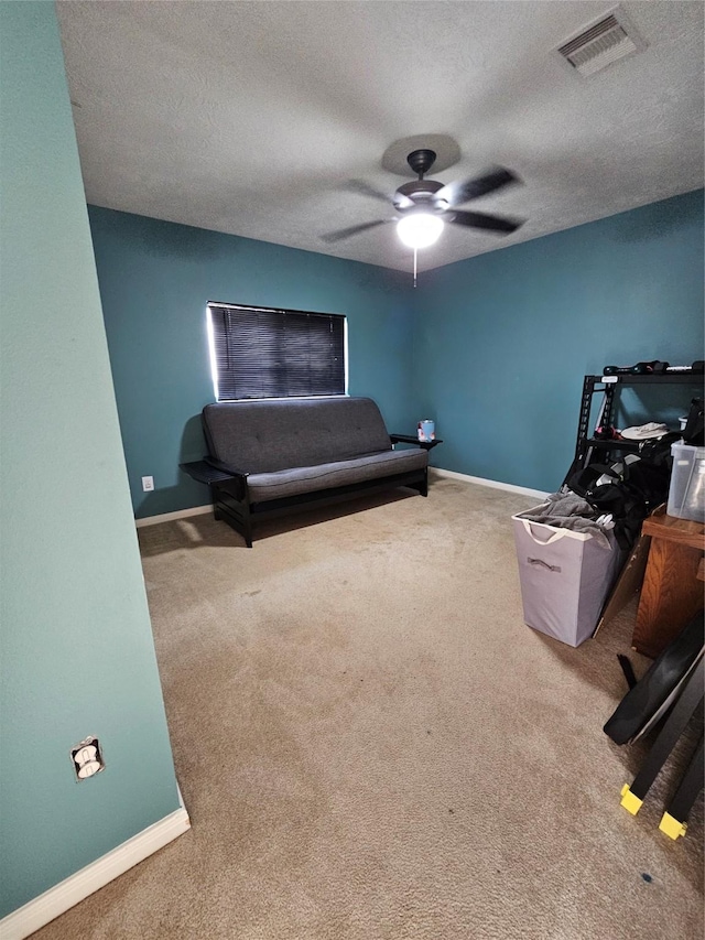 carpeted bedroom featuring ceiling fan and a textured ceiling