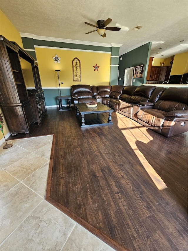 living room featuring a textured ceiling, hardwood / wood-style flooring, ceiling fan, and crown molding