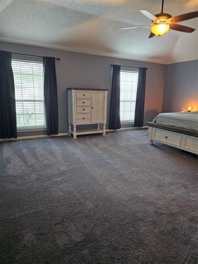 unfurnished bedroom featuring carpet, a textured ceiling, multiple windows, and ceiling fan