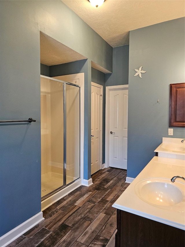 bathroom with a textured ceiling, hardwood / wood-style flooring, and walk in shower