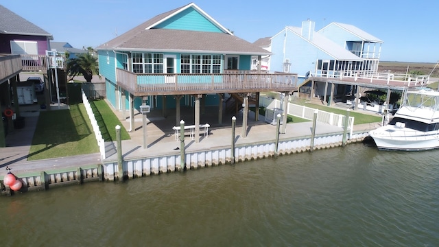 back of house with a patio area, a lawn, and a deck with water view