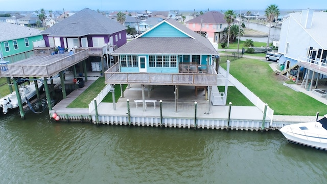 rear view of property with a yard, a patio area, and a deck with water view