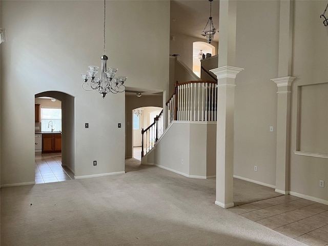 interior space with light carpet, a towering ceiling, decorative columns, sink, and a chandelier