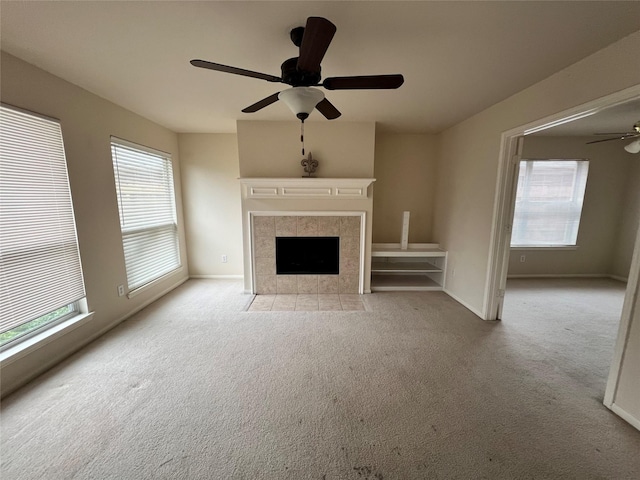 unfurnished living room with ceiling fan, light colored carpet, and a fireplace