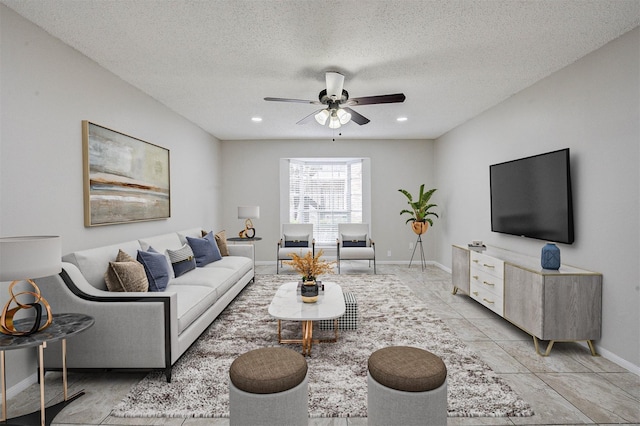 living room with ceiling fan, light tile patterned flooring, and a textured ceiling