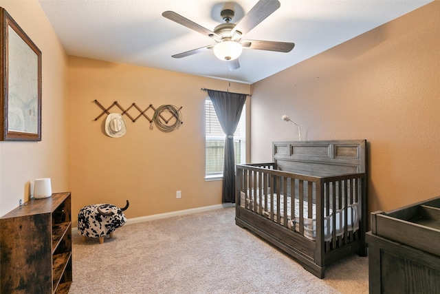 carpeted bedroom with ceiling fan and a crib