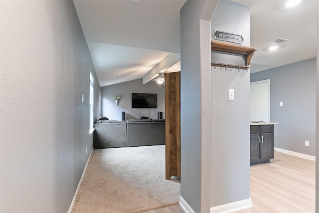 hall with light hardwood / wood-style flooring and vaulted ceiling