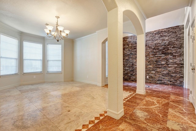 empty room featuring a chandelier, a textured ceiling, and ornamental molding