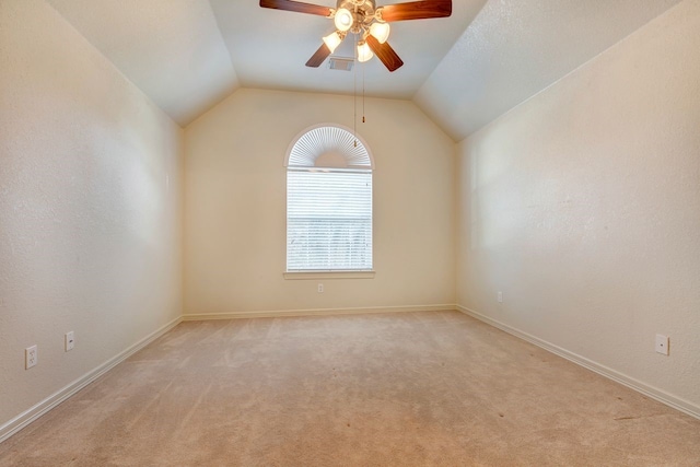 empty room featuring ceiling fan, light colored carpet, and vaulted ceiling