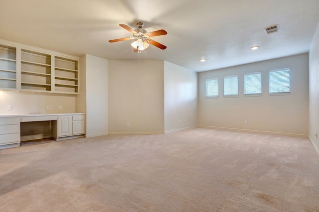 interior space with light carpet, ceiling fan, and built in desk