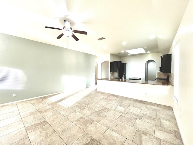 interior space featuring ceiling fan, kitchen peninsula, sink, and light tile patterned floors