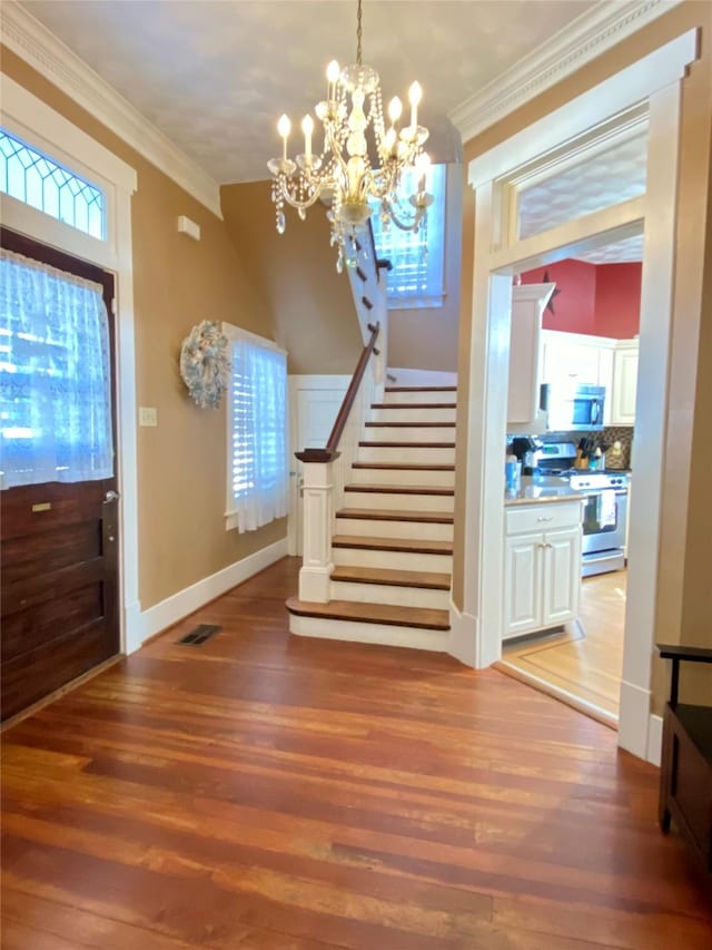 entryway with a chandelier, hardwood / wood-style floors, plenty of natural light, and crown molding