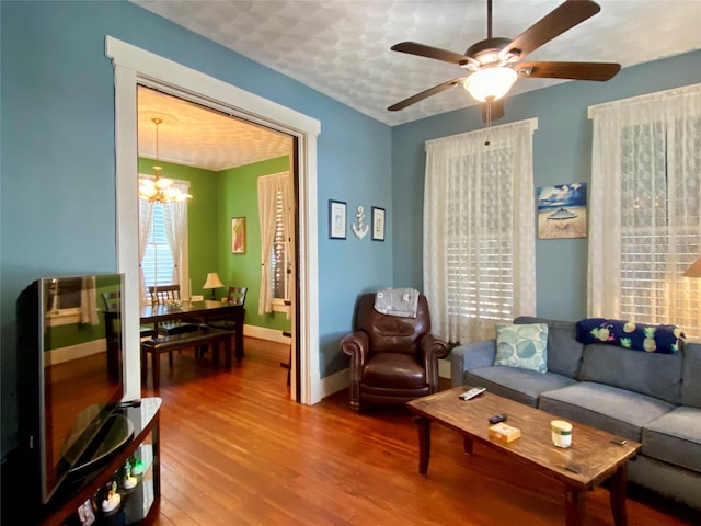 living room featuring wood-type flooring and ceiling fan with notable chandelier