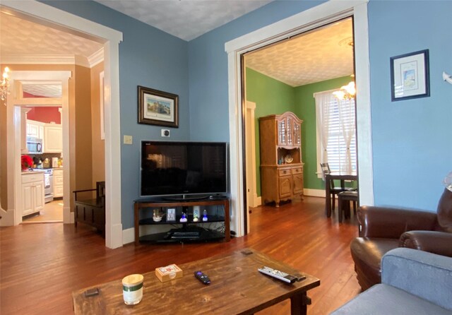 living room with hardwood / wood-style floors, a notable chandelier, and ornamental molding