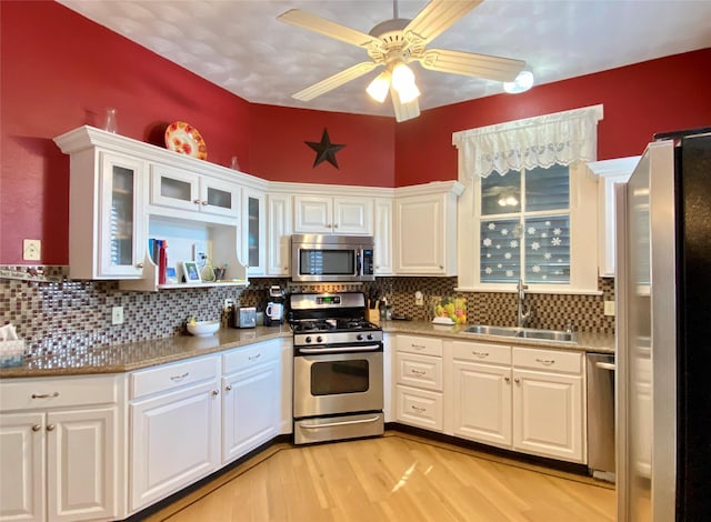 kitchen with decorative backsplash, appliances with stainless steel finishes, sink, white cabinets, and light hardwood / wood-style floors