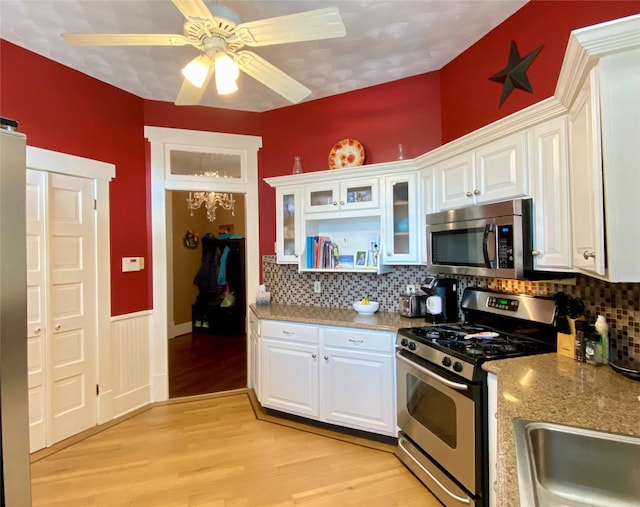 kitchen featuring appliances with stainless steel finishes, backsplash, light hardwood / wood-style floors, and white cabinetry