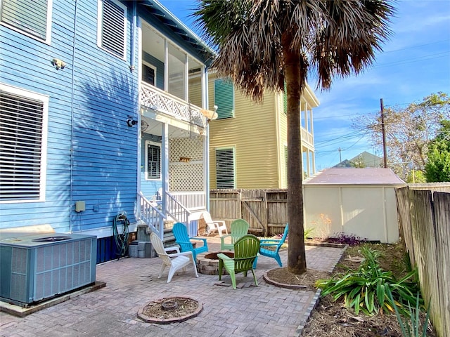 view of patio / terrace with central air condition unit, a balcony, a fire pit, and a storage unit