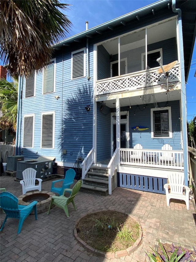 back of property featuring a patio area, a balcony, and an outdoor fire pit