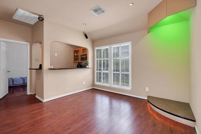 unfurnished living room featuring dark wood-type flooring and vaulted ceiling