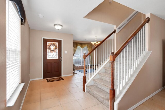 entryway featuring an inviting chandelier and light tile patterned flooring