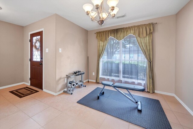 workout room featuring tile patterned floors, a healthy amount of sunlight, and a notable chandelier