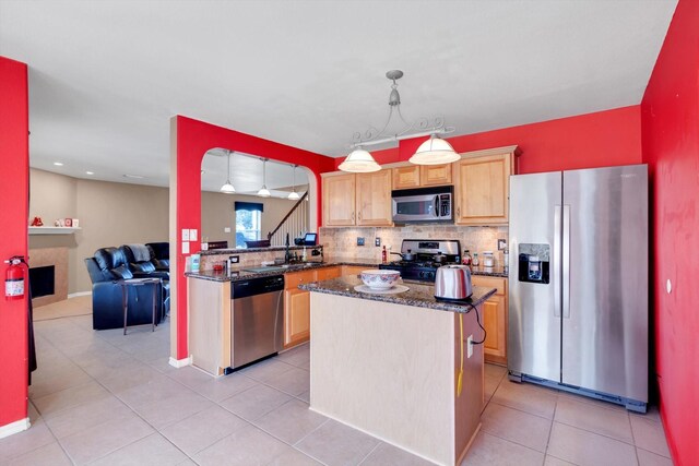 kitchen with backsplash, dark stone counters, stainless steel appliances, a kitchen island, and hanging light fixtures