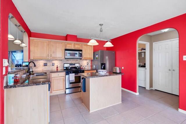 kitchen featuring sink, hanging light fixtures, light brown cabinetry, appliances with stainless steel finishes, and a kitchen island