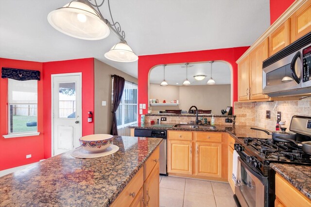 kitchen with sink, backsplash, dark stone counters, pendant lighting, and appliances with stainless steel finishes