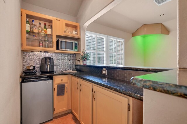 kitchen featuring lofted ceiling, stainless steel appliances, dark stone counters, and tasteful backsplash