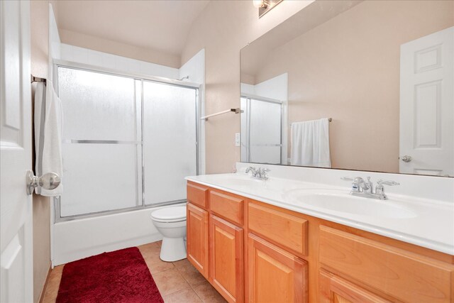 full bathroom featuring shower / bath combination with glass door, vanity, tile patterned floors, and toilet