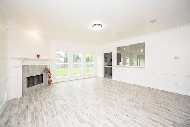 unfurnished living room with a fireplace, light hardwood / wood-style floors, and crown molding