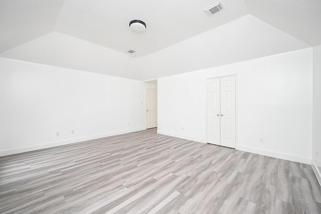 empty room with vaulted ceiling and light hardwood / wood-style flooring