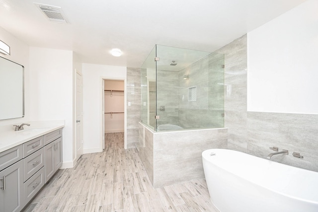 bathroom featuring hardwood / wood-style floors, vanity, and plus walk in shower