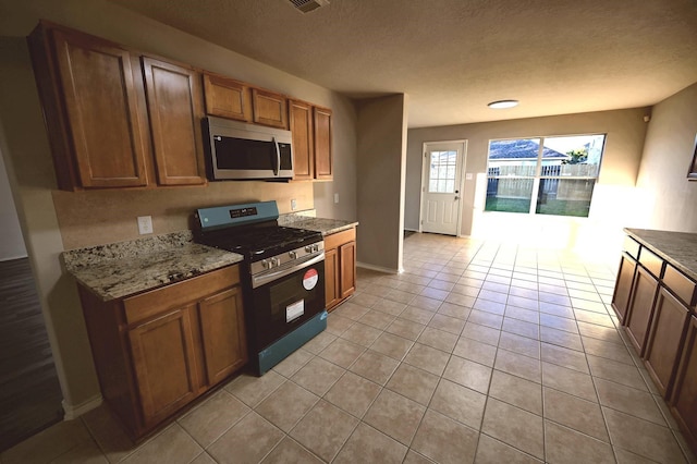 kitchen featuring light stone countertops, light tile patterned floors, and stainless steel appliances