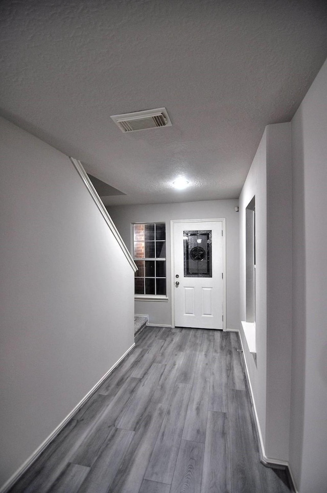 corridor featuring a textured ceiling and hardwood / wood-style floors