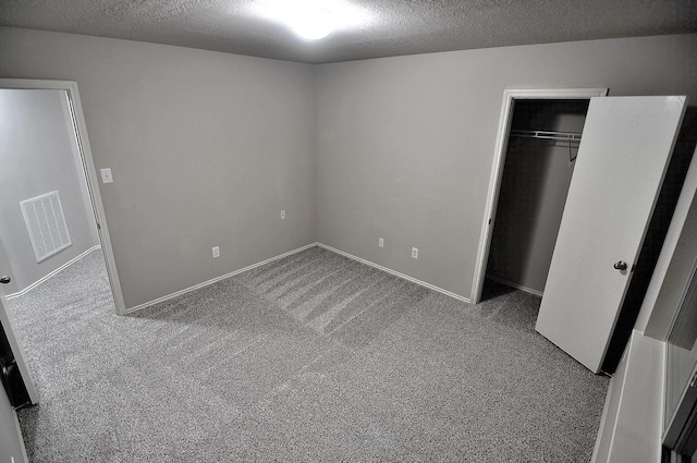 unfurnished bedroom with carpet floors, a closet, and a textured ceiling