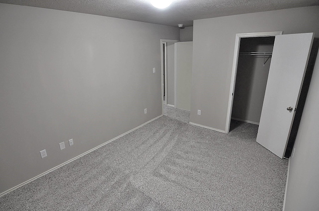 unfurnished bedroom featuring light carpet, a closet, and a textured ceiling