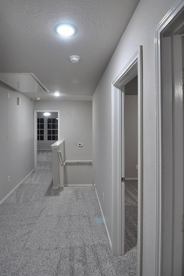 hall with a textured ceiling and carpet floors