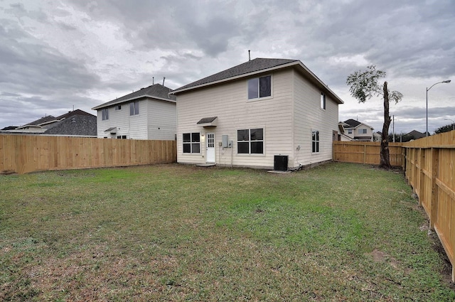 back of house with central AC and a lawn