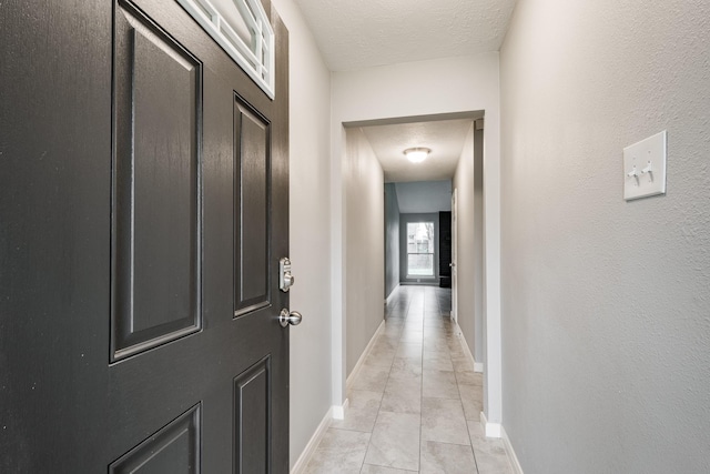 hall featuring light tile patterned floors and a textured ceiling