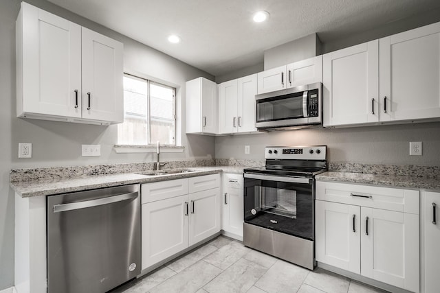 kitchen featuring light stone countertops, sink, white cabinetry, and stainless steel appliances