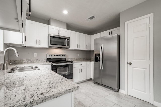 kitchen with light stone counters, sink, white cabinetry, and stainless steel appliances